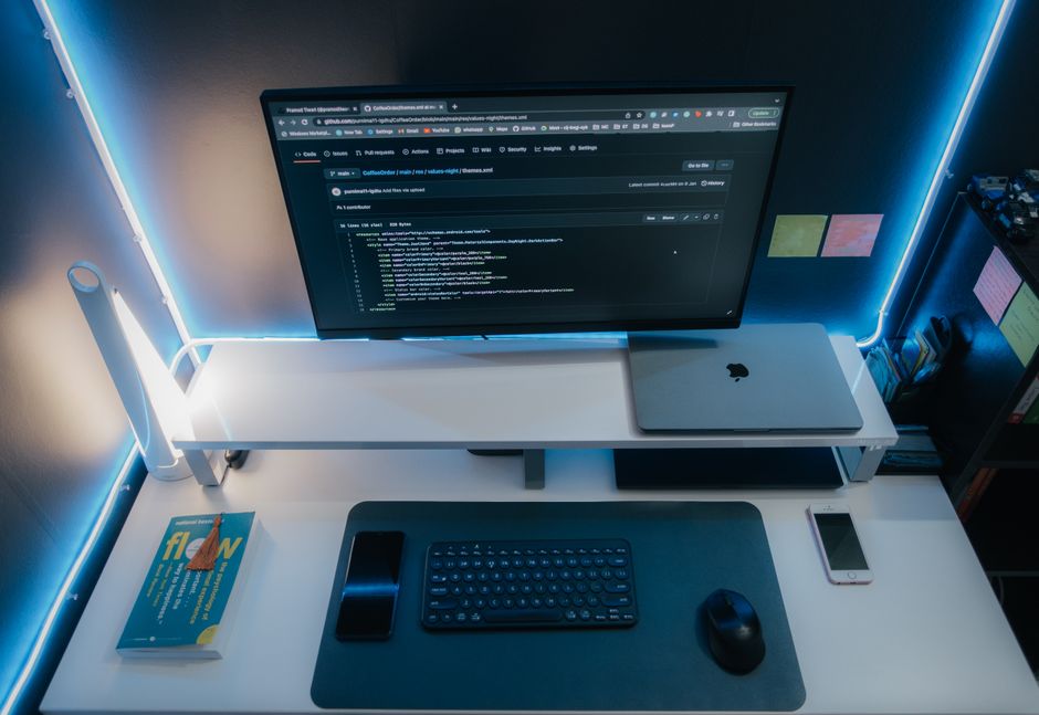A minimalist workspace with a computer setup and neon lighting